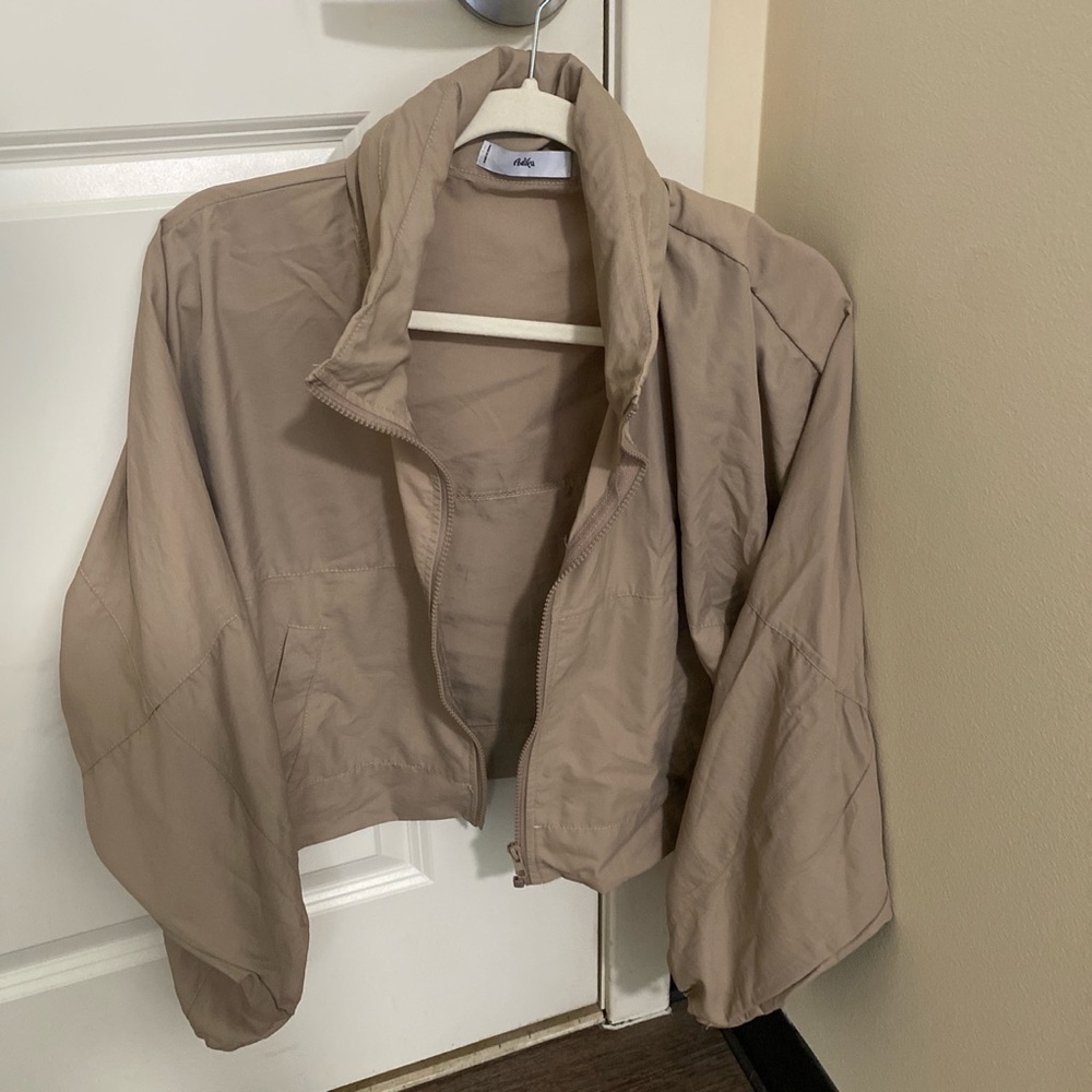 Adika beige cropped windbreaker with hidden hood zipped into collar.